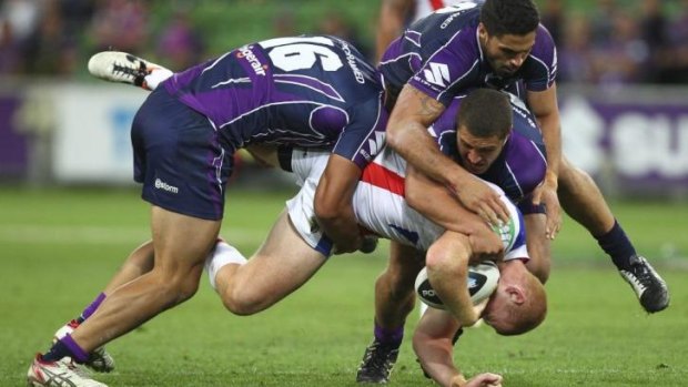 Alex McKinnon falls awkwardly in the three-man Storm tackle.