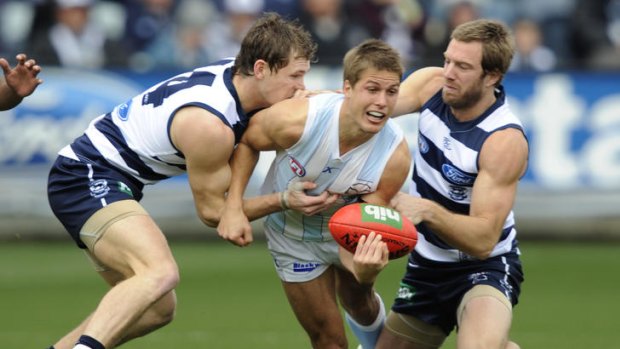 North's Andrew Swallow tackled by Geelong's Joel Selwood and Joel Corey.
