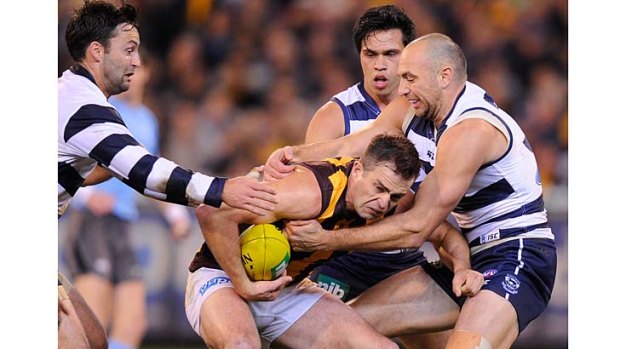 Swamped: Hawk Brian Lake is tackled by Cats James Podsiadly and Jimmy Bartel (left), watched by teammate Allen Christensen.