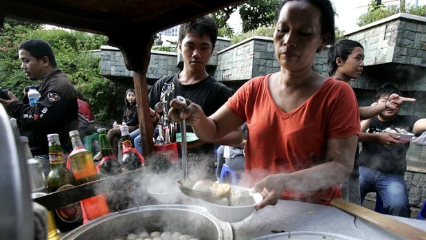 Meatball mystery: A street vendor serves up a dish of bakso, and while fans such as the woman below don't know what's in them, they can't get enough.