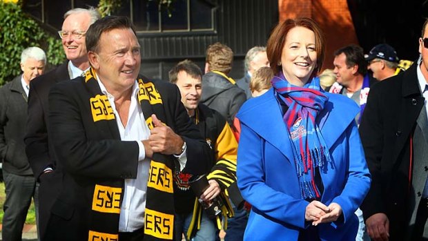 Prime Minister Julia Gillard and partner Tim Mathieson walk to the MCG wearing their team colours.