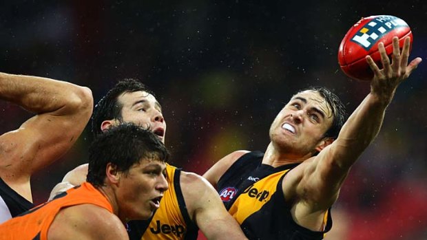 Full stretch: The Tigers' Ben Griffiths makes a greasy ball stick in a sodden match in Sydney yesterday.