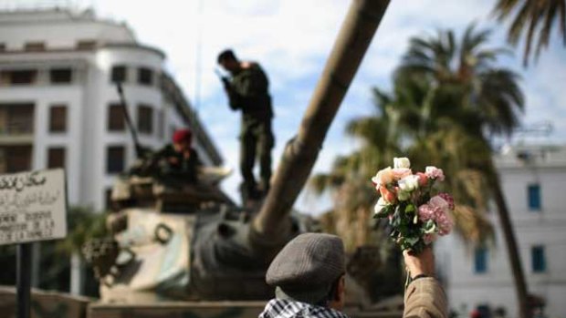 A protester offers flowers to soldiers in Tunis after street rallies helped oust the Tunisian president.