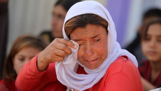 A displaced Iraqi Yazidi woman wipes her eyes.