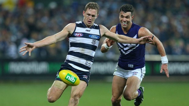 Joel Selwood, sporting a cut eye, gets a rare kick against Ryan Crowley during the Cats' win over the Dockers.