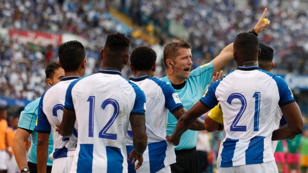 Referee Daniele Orsato warns off Honduran players as they plead for him to reverse a penalty call in their World Cup qualifier against Australia at the Olympic Stadium in San Pedro Sula.