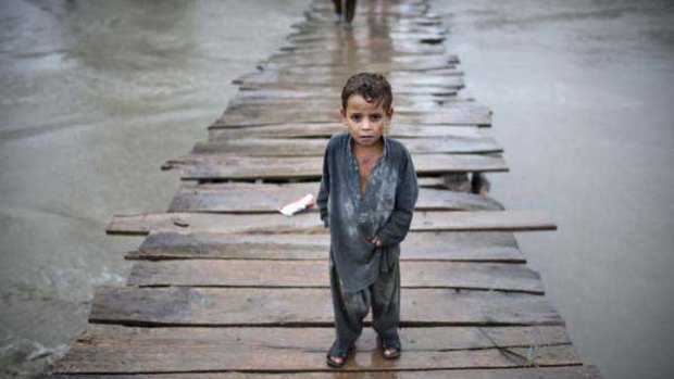 A Pakistani child makes a dangerous crossing on a wooden bridge towards the village of Shah Alam on the outskirts of Peshawar. <i>Picture:  AFP</i>