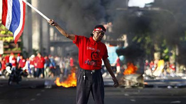 A protester makes a lone stand as tyres burn in the background.