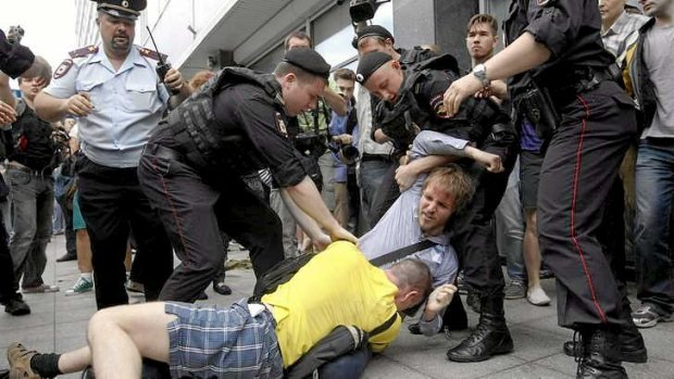Policemen break up a fight between a gay rights activist and an anti-gay rights activist (in yellow) during a protest against a new law "against advocating the rejection of traditional family values".