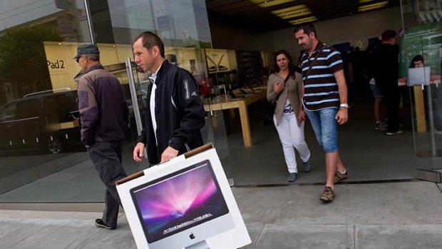A man walks out of an Apple store with a computer in San Francisco.