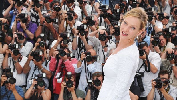 Actor and jury member Uma Thurman strikes a pose in a silk white Versace gown at the opening of the Cannes Film Festival.