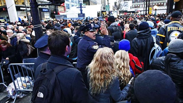 A New York Police officer tries to control fans as they gather en masse at Super Bowl Boulevard on Saturday.