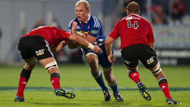 Schalk Burger of the Stormers is tackled by Sam Whitelock (L) and Luke Romano of the Crusaders.