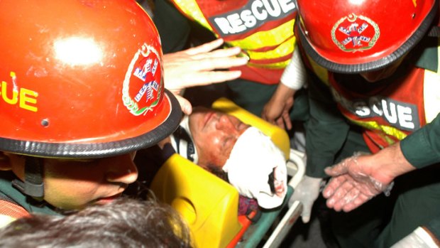 Rescue workers carry a bloodied Imran Khan to a Lahore hospital after he fell off a lift taking him onto the stage for an election rally.