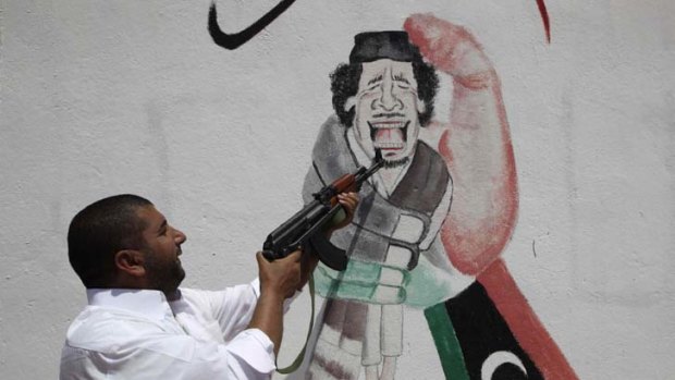 In the firing line &#8230; a rebel fighter points his gun at a graffiti image of Muammar Gaddafi.
