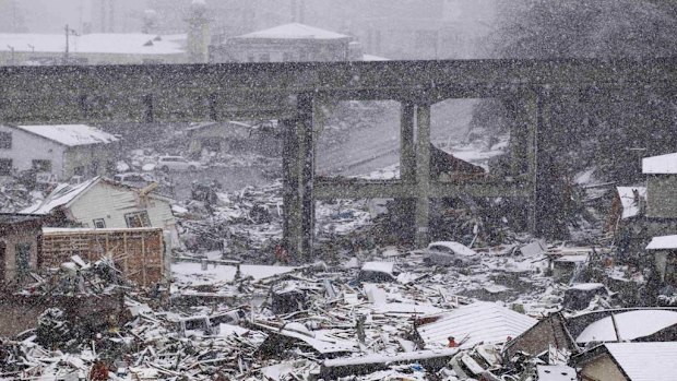 Members of a British search and rescue team search for trapped people as snow falls in Kamaishi.