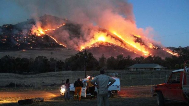 A controlled backburn lights up a mountain in Adjungbilly, where farmer Tony Engel's house sits safely in front of the trees that line the Murrumbidgee River.