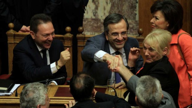 Greek Finance Minister Yannis Stournaras (L) and Greek Prime minister Antonis Samaras (2L) are congratulated by lawmakers after a parliament vote in Athens, on early July 18, 2013. AFP Photo.