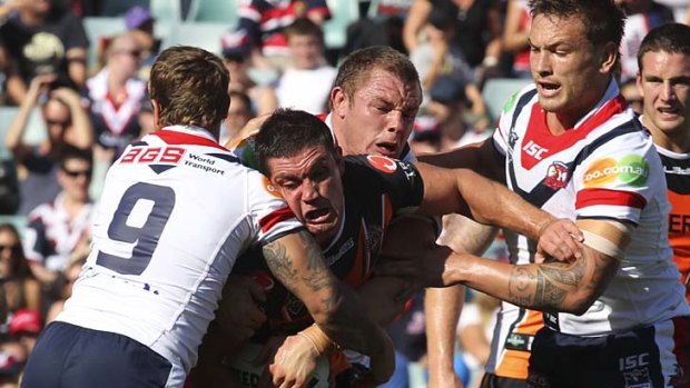 Safety in numbers . . . Rooster Jake Friend, lft, gets plenty of help to tackle Wests Tigers forward Chris Heighington at the Sydney Football Stadium yesterday.