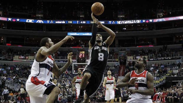 San Antonio Spurs guard Patty Mills goes up to shoot between Washington Wizards forwards Trevor Ariza and Martell Webster  in the second overtime period. The Spurs won 125-118.