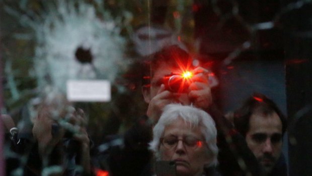 Onlookers photograph bullet holes in the door of Salle a L'etage, one of the sites of the terrorist attacks in Paris.