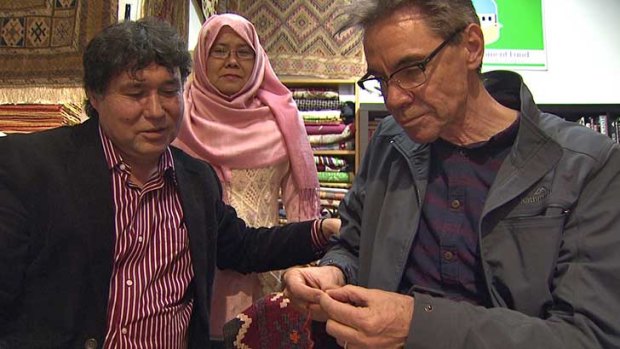 Rugmaker/author Najaf Mazari tries to teach Steve Thomas some rug repairing skills, watched by Najaf’s wife Hakima.