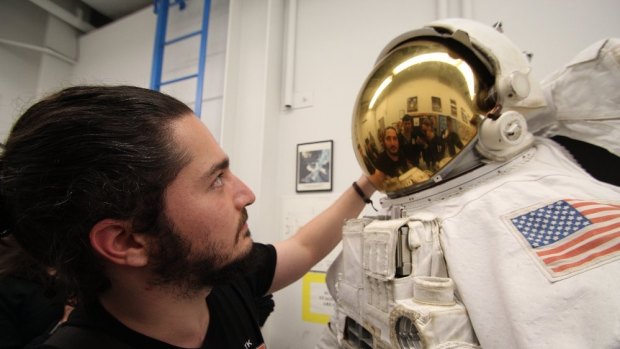 Emre Deniz checks out the bubble helmet on a NASA suit.