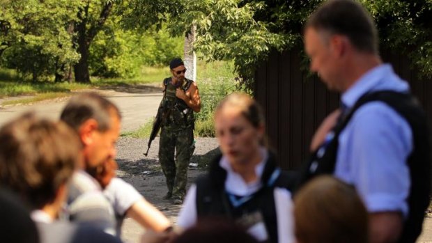 Yuri a pro-Russian rebel stands in the background as OSCE mission Alexander Hug (right) talks to residents of Rassypnoe.
