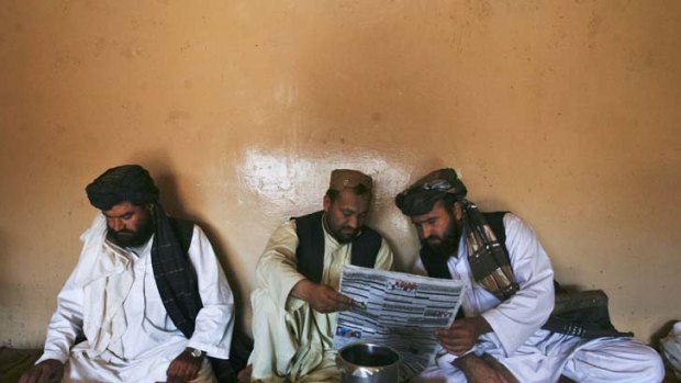 Pashtun men read local newspapers reporting the arrest of senior al Qaeda leader Younis al- Mauritani.