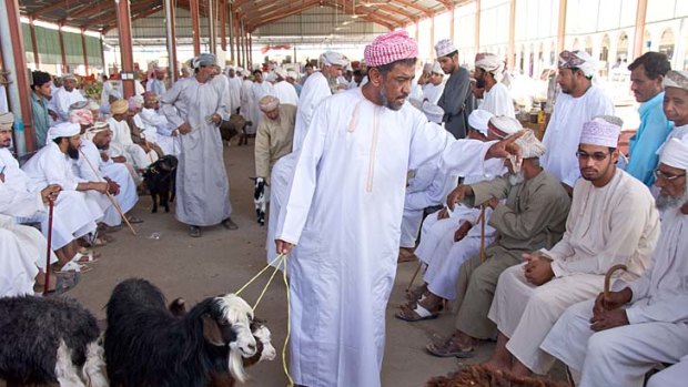 An auctioneer haggles over the price of a goat in Ibra Souq.