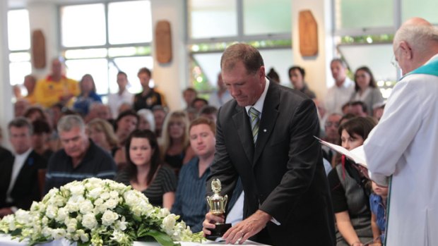 Steve Barclay places a trophy on top of his son Matt Barclay's coffin.