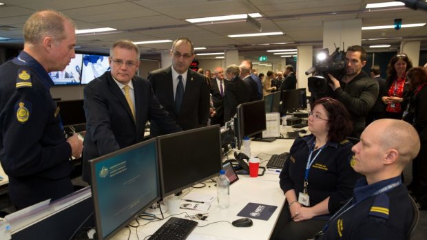 Minister for Immigration and Border Protection Scott Morrison and acting-Commander of Strategic Border Protection Terry Price talk with operations officers at the National Border Targeting Centre launch in Canberra.