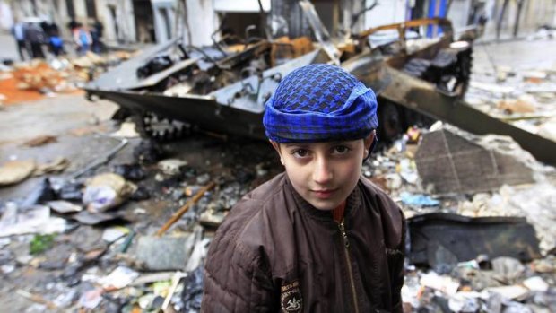 A Syrian boy stands in front of a damaged armoured vehicle belonging to the Syrian army in Homs.