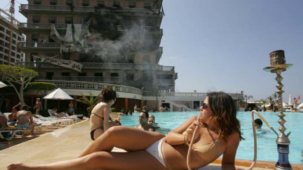 Patching up ... visitors enjoy the swimming pool of Beirut's bombed landmark Saint-Georges hotel.