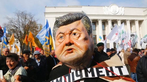A protester wearing President Petro Poroshenko's mask, with the writing 'Impeachment' on his breast, attends a rally outside the Ukrainian parliament in October.