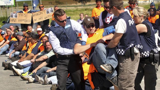 Police arrest a picketing worker outside the Visy carboard plant in Dandenong yesterday. The action allowed trucks to enter the site for the first time in more than a week.