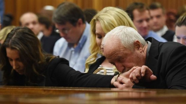 The father of defendant Oscar Pistorius, Henke  kisses the hand of his daughter Aimee as as a judge began handing down her verdict.