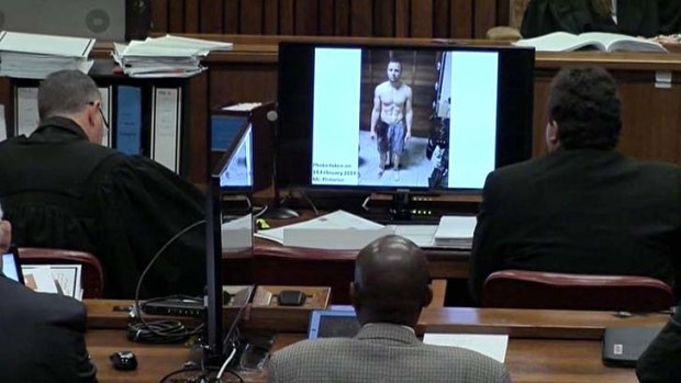 A police photograph of Oscar Pistorius standing on his blood-stained prosthetic legs and wearing shorts covered in blood, taken shortly after the athlete fatally shot his girlfriend, is viewed in court.