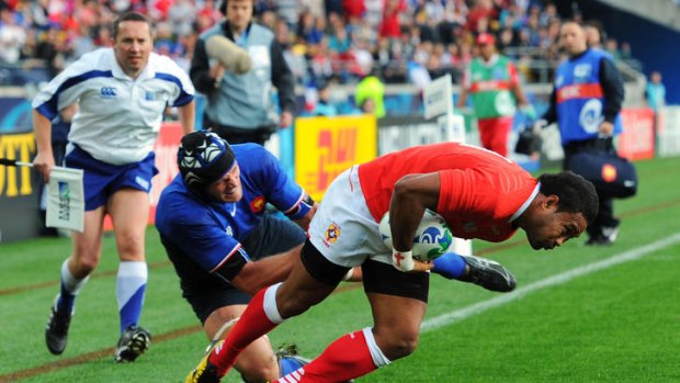 Wing Sukanaivalu Hufanga of Tonga breaks through the challenge of Julien Bonnaire of France to score the opening try.