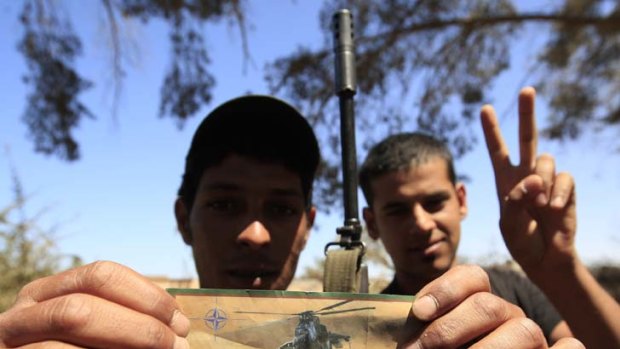 Paper propaganda ... a rebel holds a flyer dropped by NATO aircraft that warns Gaddafi troops to stop fighting "or when you see this helicopter it will be too late".
