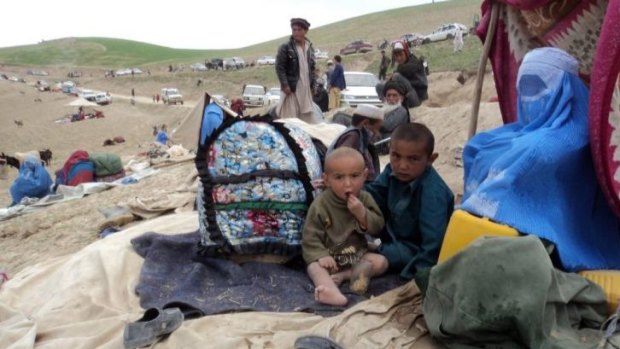 Survivors sit with their possessions near the site of the landslide that buried Aab-Bareek village.