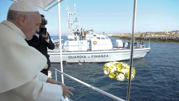 Remembering migrants lost at sea: Pope Francis throws flowers into the sea from a boat on Lampedusa.