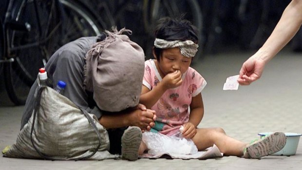 Inequality poses a problem in China - and the US. A woman and a child beg on the street in Beijing.