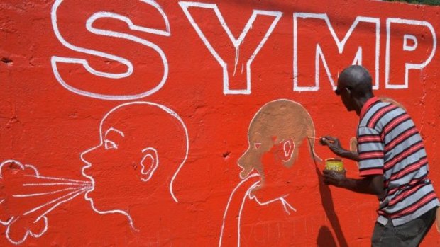 Liberian street artist Stephen Doe paints a mural to inform people about the symptoms of the deadly Ebola virus in Monrovia.