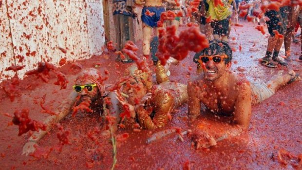People lay in a puddle of squashed tomatoes during the annual "tomatina" fiesta.