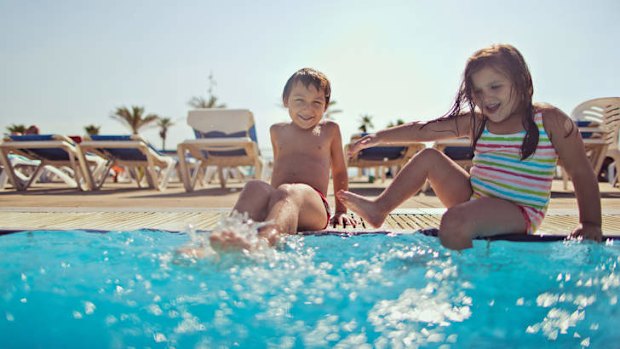 Siblings enjoy an outdoor swimming pool.