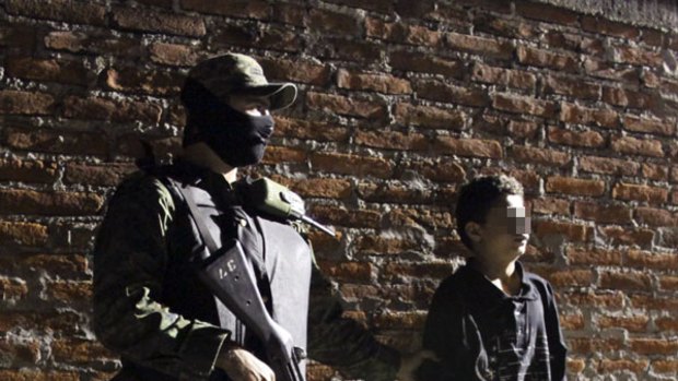 A soldier stands with Edgar Jimenez, a suspected drug gang hitman, in Mexico.