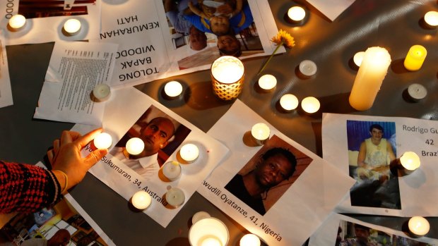 A woman places a candle on top of pictures of the executed prisoners at a vigil in Sydney.