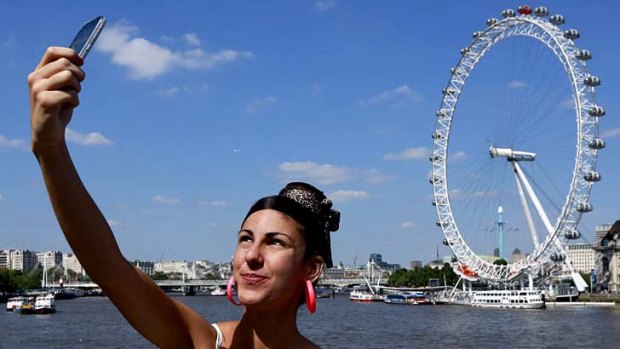 A tourist takes a picture of herself in front of the River Thames and the London Eye. New figures show London has overtaken Paris as the world's most visited city.