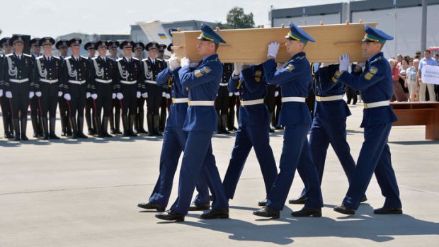 Ukrainian soldiers carry a coffin of one of the MH17 victims on to a military plane at Kharkiv airport.